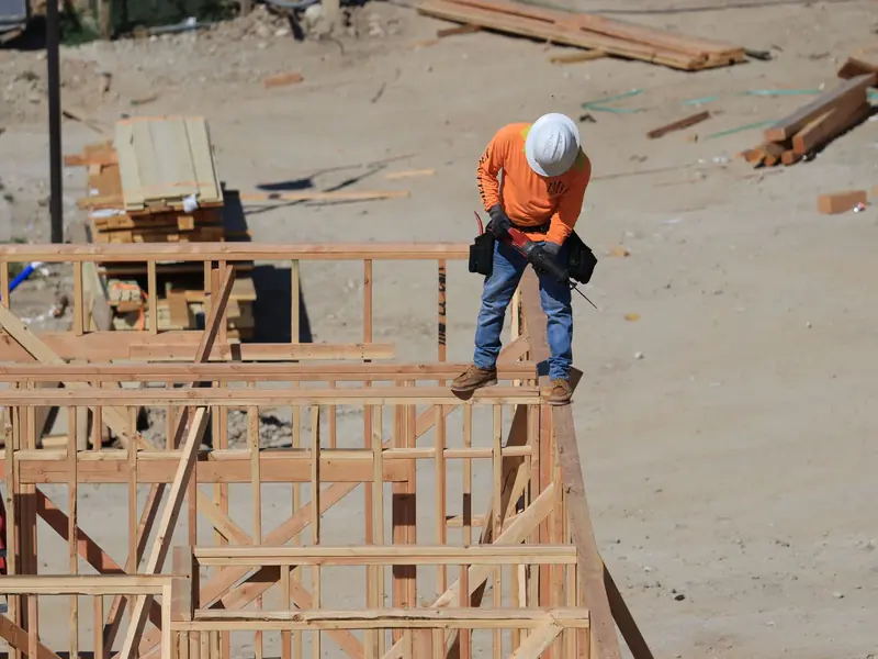 Worker with a drill on a house frame