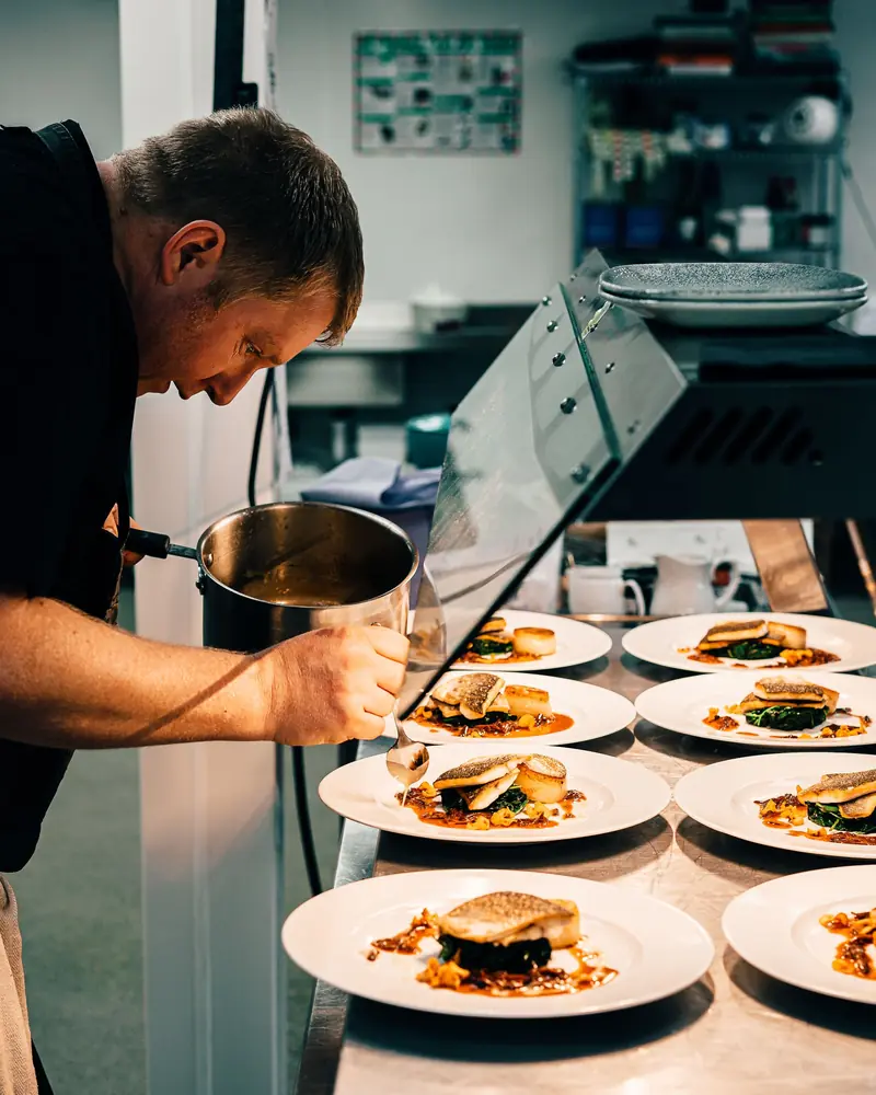 Chef finishing a row of plated dishes